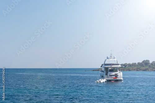 White yacht and small white boat anchored near shore