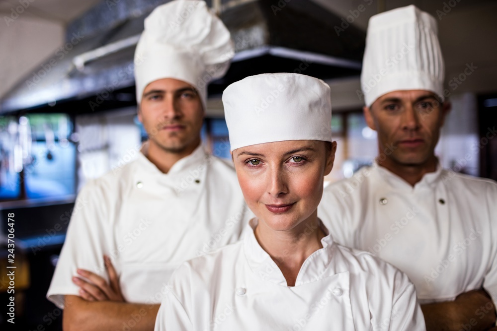 Group of chefs standing with arms crossed in kitchen