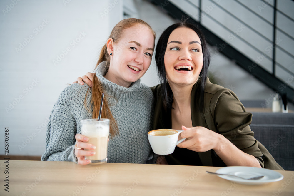 Two women are holding coffee mug. Sitting on the couch talking about the job in the morning. One cup of coffee will make the body and brain fresh.