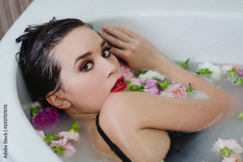 Obraz premium beautiful sexy sad young slim brunette woman in spa - bathroom with water and flowers