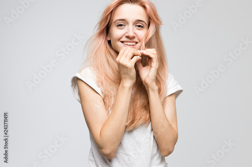 Cropped studio portrait of cute young inspired girl in white t-shirt looking at camera and smile  holds hand to face good-looking  cheerful lady  satisfaction  people  beauty and lifestyle concept.