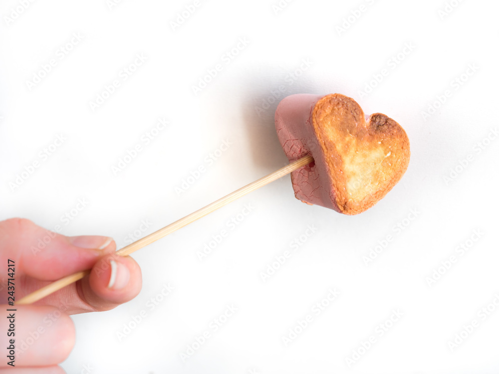 roasted heart form marshmallows on a skewer in female hand on white background roasted heart form marshmallows on a skewer in female hand on white background
