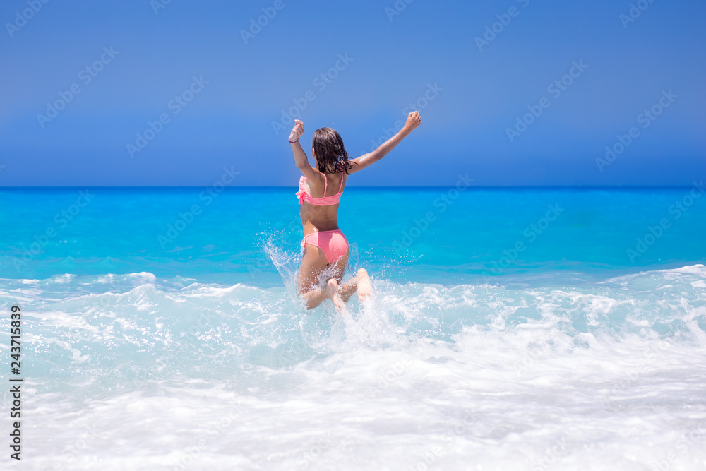 Happy young female kid playing with waves in the ocean Happy young female kid playing with waves in the ocean