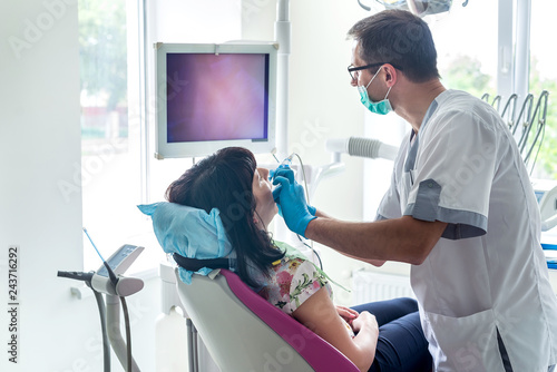 Dentist examining patient teeth with intraoral camera photo