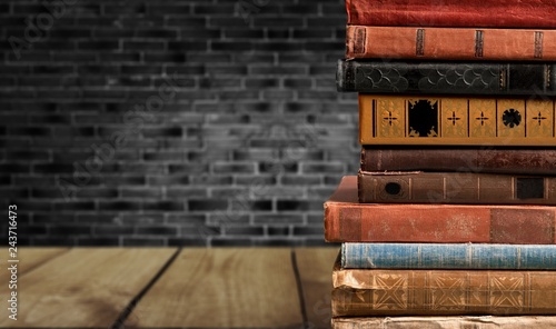 Collection of old books on wooden table on room background
