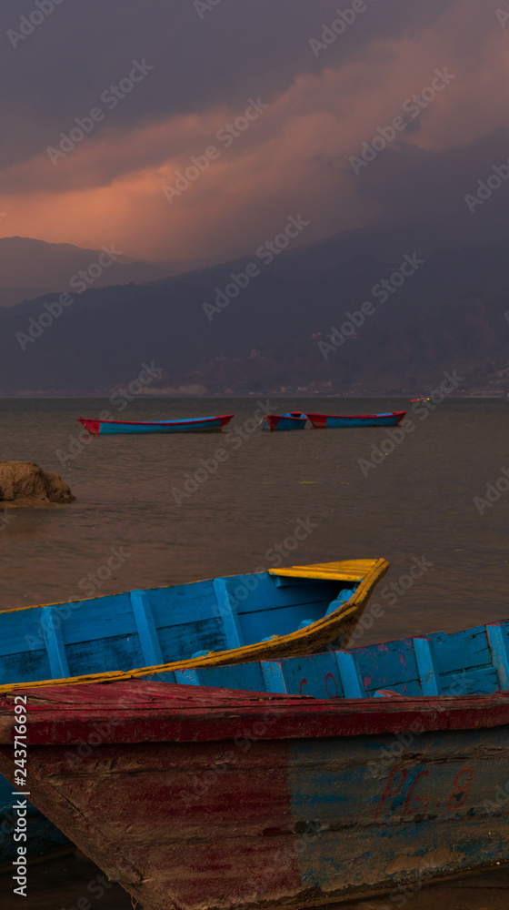 Boats in Pokhara lake in Nepal during sunset in a rainstorm. 