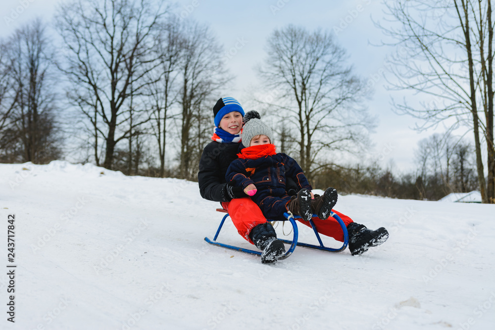 boy and girl are riding on sleds