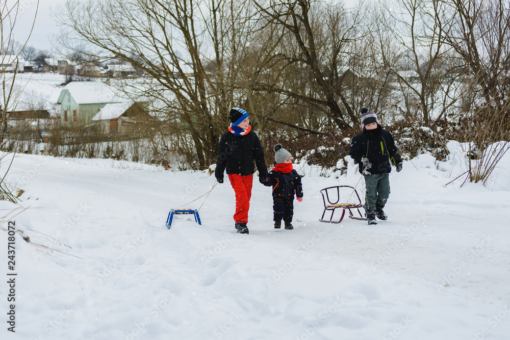 Three children are dragging sleigh in the mountain