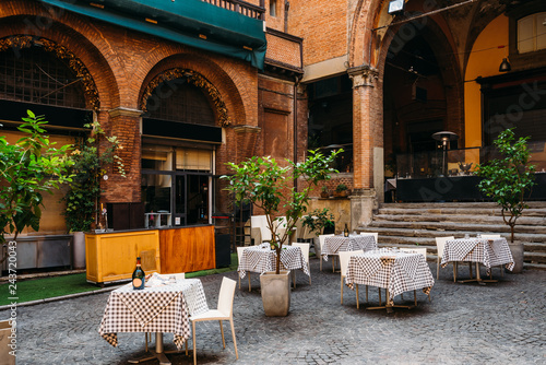 Fotografie Old narrow street with tables of restaurant in Bologna, Emilia Romagna, Italy