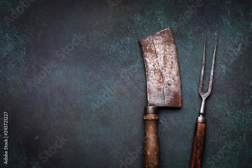 Vintage meat cleaver and fork on grunge concrete background with copy space