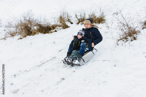 Dad and son ride in sledding, baby is fun