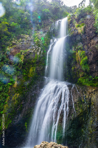 Long exposure falling water view of Kitekite Falls on Piha Beach  scenic 3-tiered waterfall near Auckland. North Island  New Zealand.