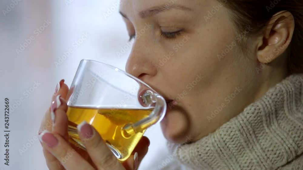 Young woman enjoying her morning coffee or tea looking at snow outside the window Young woman enjoying her morning coffee or tea looking at snow outside the window