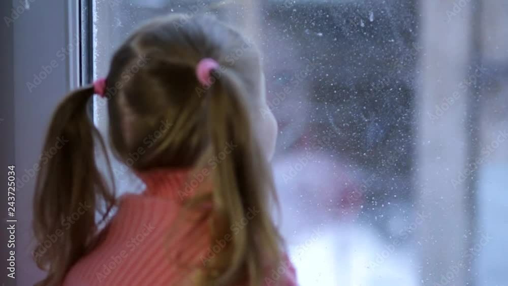 a little girl sitting on a windowsill on a cloudy morning a little girl sitting on a windowsill on a cloudy morning
