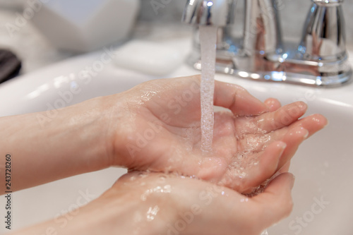 Young Caucasian Female Hands Lathering White Bar Hand Soap for Washing and Personal Hygiene  and Then Rinsing Hand Under Sink Water at Clean Home Bathroom