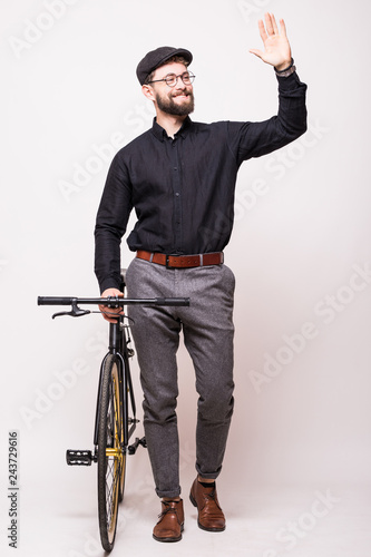 Portrait of a bearded handsome young man walking with fixie bicycle and wave hello gesture over white background