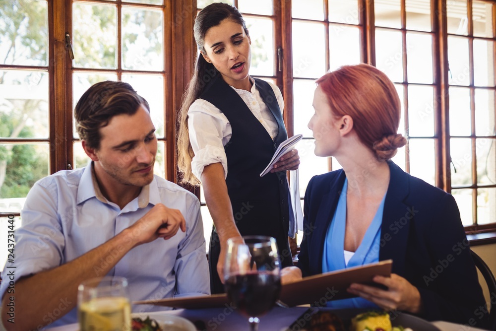 Business people discussing menu card with waitress