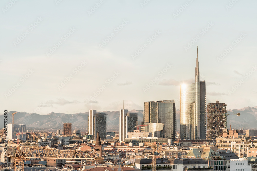 Milan skyline with modern skyscrapers in Porta Nuova business district in Italy. Panoramic view of Milano city. The mountain range of the Lombardy Alps in the background.