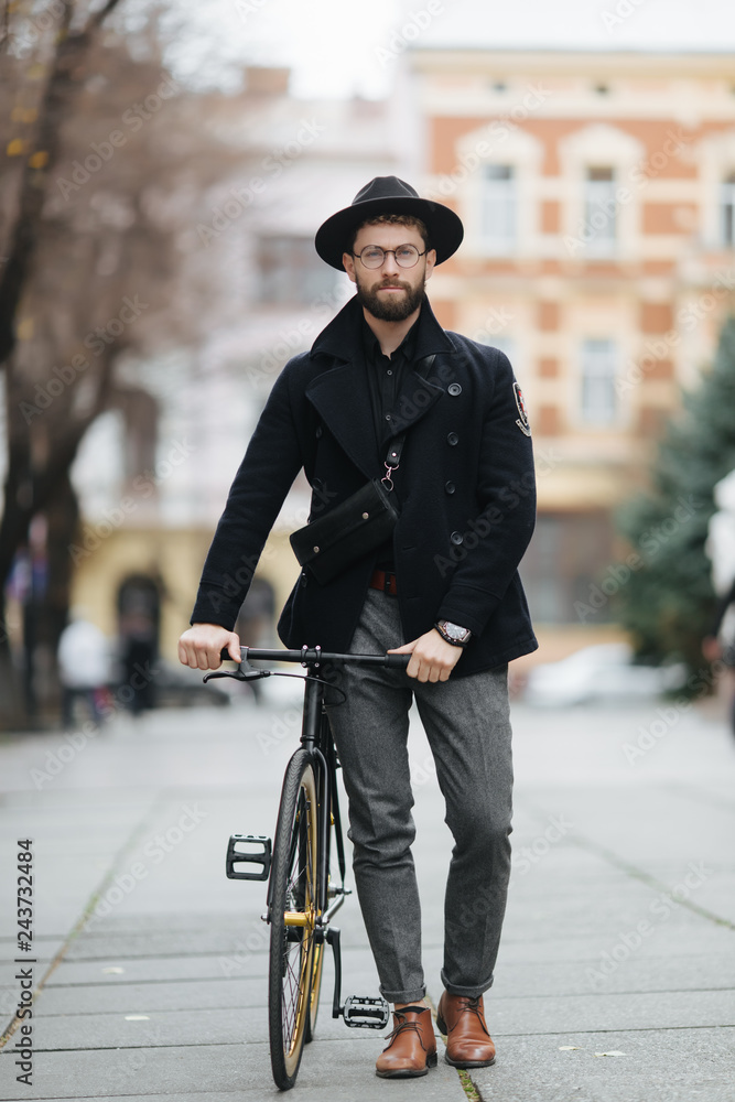 City bike. Handsome young man with a beard walk the city with bicycle