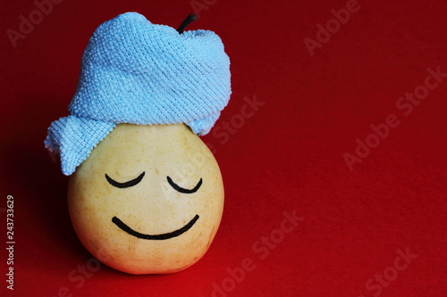 Spa salon. Relaxed happy yellow pear with blue towel on red background. Art idea.
