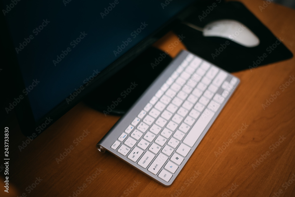 A aluminum grey desktop personal computer PC with wireless keyboard, mouse on the wood table desk isolated white. A aluminum grey desktop personal computer PC with wireless keyboard, mouse on the wood table desk isolated white.