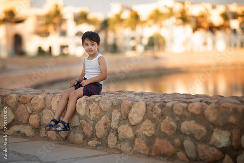 boy sitting on the stone border © Natalia