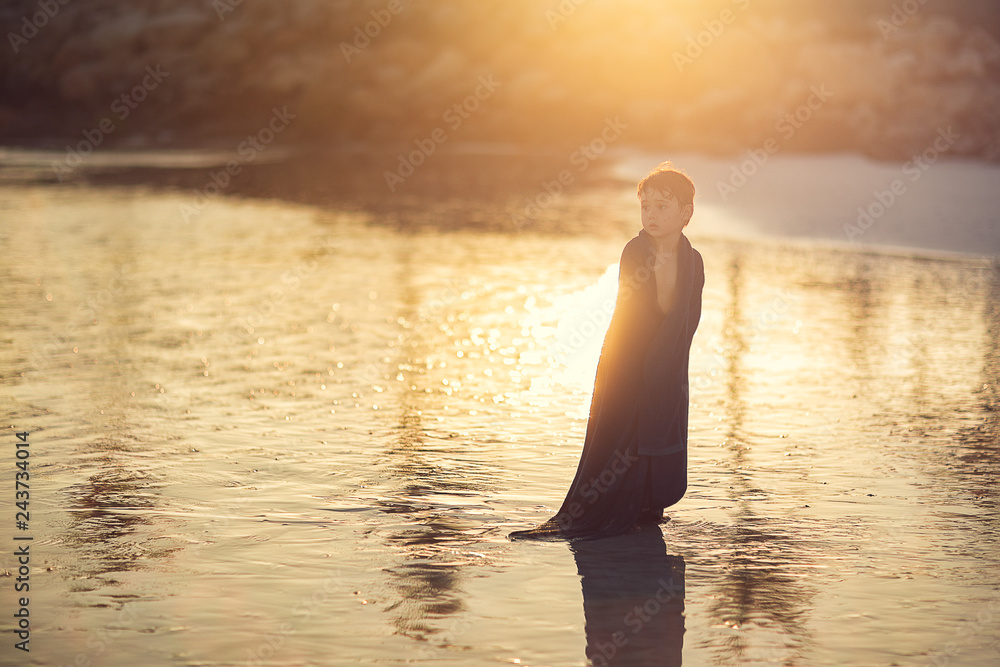 Fototapeta premium boy wrapped in big towel standing on the beach