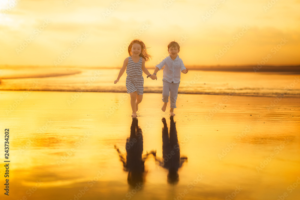 boy and girl holding hands running on the beach