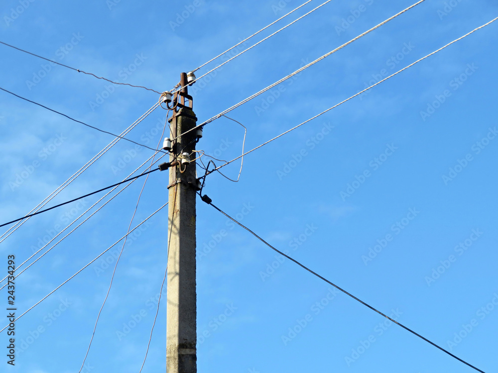 Old power line post with electrical wires and capacitors isolated on blue sky background. Electricity transmission line, power supply Old power line post with electrical wires and capacitors isolated on blue sky background. Electricity transmission line, power supply