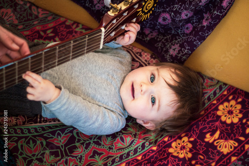 baby is making music with a guitar at home photo