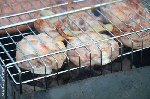 Preparation on bbq. Dish with roasted meat on abstract background. Hot tasty smokey barbecue meal at coals and burnt firewood. Cooking on fire outdoor. Nice smelling food. Fried chiken pieces photo