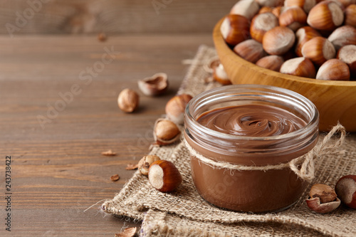 Chocolate spread with hazelnuts on wooden background photo