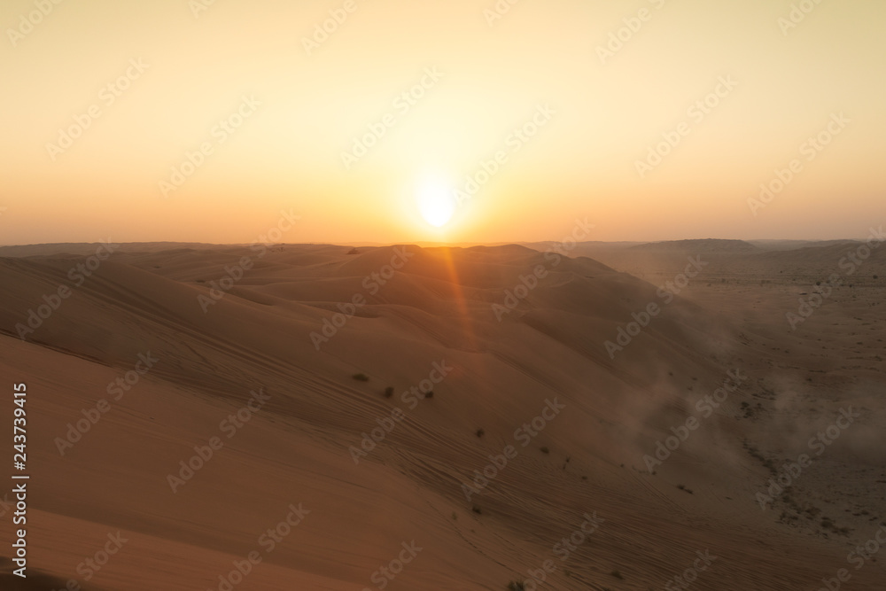 sun setting behind dunes
