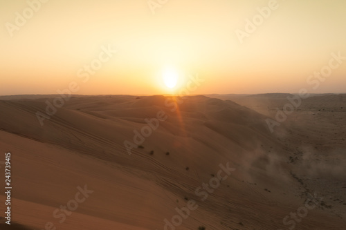 sun setting behind dunes