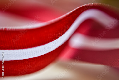 Latvia's flag ribbon on white blur background. Selective focus