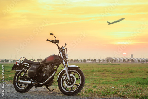 Vintage motorcycle with blurry plane at sunset. photo