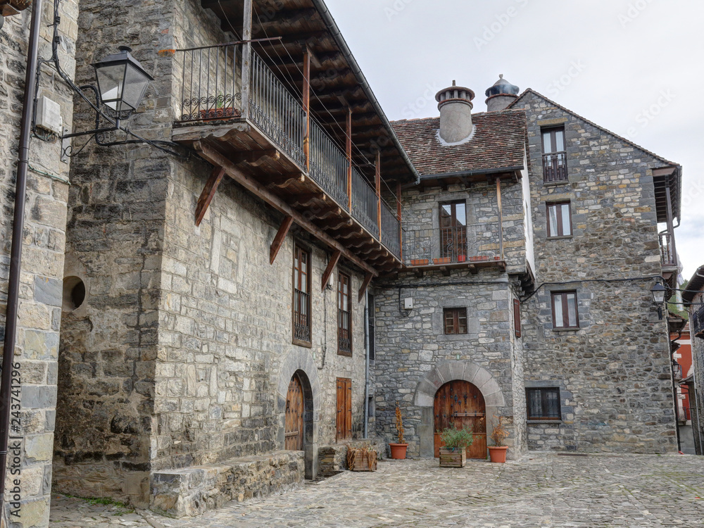 A rural landscape of a mountain hamlet with some stone houses with wooden balconies and dark roofs during winter in Ansó, Aragon region, Spain