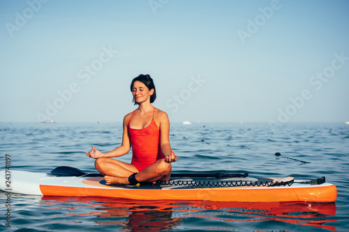 Young woman doing yoga on sup board with paddle © teksomolika