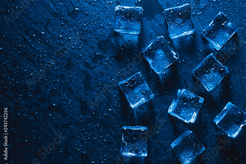 blue Pieces of ice cubes with water droops on black background. advertising photo