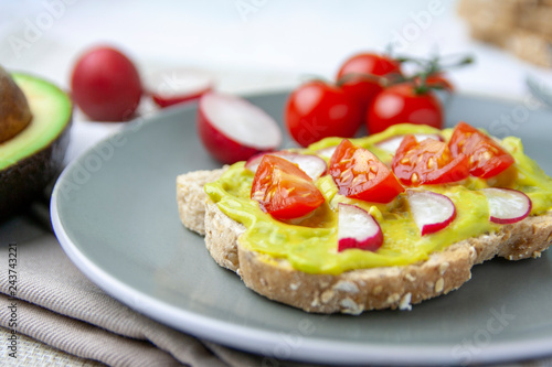 Healthy meal with toast with avocado, tomato and radish on a plate and the ingredients