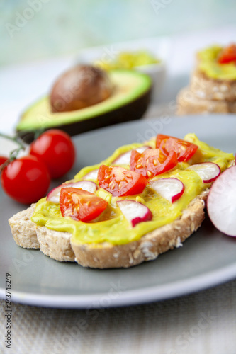 Healthy toast with avocado, tomato and radish on a plate and the ingredients