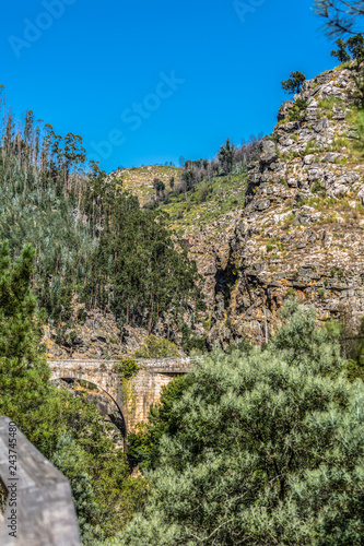 View of mountains and a old roman bridge over Paiva river, in stone, with vegetation around