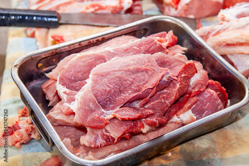 pork, from slaughter to the kitchen, raw fresh steaks ready for cooking on the grill, in a metal container, homemade