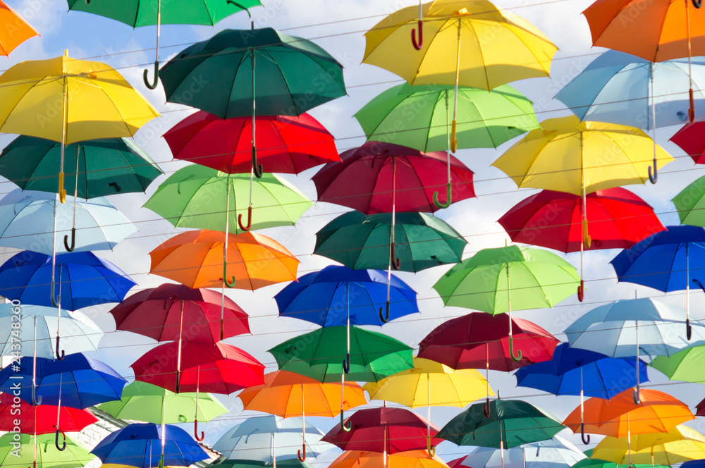 umbrellas of different colors soar in the summer sky