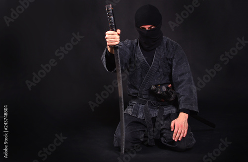 Tired ninja in kimono with katana sits on his lap