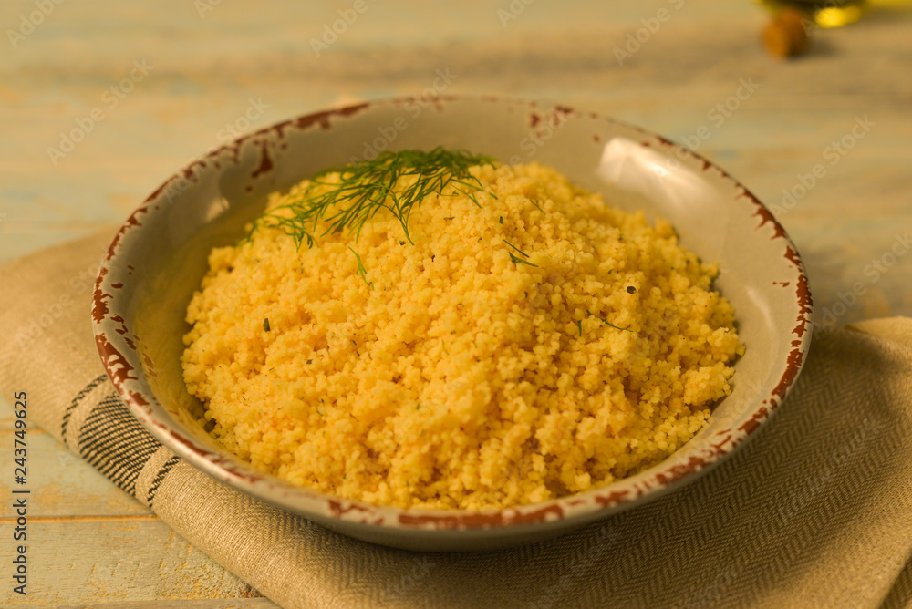 Traditional Couscous with seasoning in grey bowl on wooden table closeup Traditional Couscous with seasoning in grey bowl on wooden table closeup