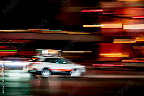 White car taxi cab in city at night with motion blur concept