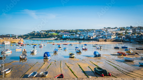 Fishing boats during low tide in the evening at sunset at the harbor of St Ives vacation, fishing town in St. Ives, Cornwall, United Kingdom, UK.