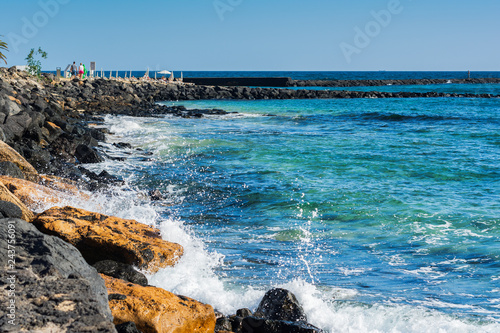 Turquoise waters in Las Cucharas beach, Lanzarote, Canary islands. VIew of the sea, sandy beach and rocks, selective focus