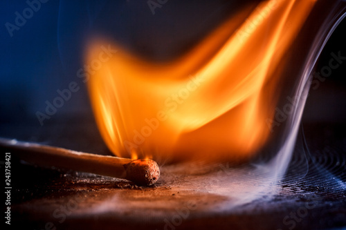 Macro shooting of a burning match with a flame of fire and smoke on a black background